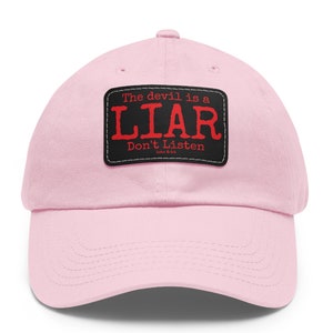 May include: Pink baseball cap with a black patch that reads "The devil is a LIAR Don't Listen John 8:44".
