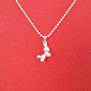May include: A silver chain necklace with a silver pendant shaped like a stylized dog. The pendant is made of multiple round beads.