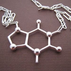 Puede incluir: Collar de plata con un colgante en forma de mol&eacute;cula de cafe&iacute;na. El colgante est&aacute; hecho de alambre de plata y tiene un acabado brillante.