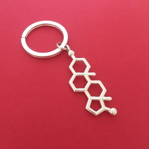 May include: Silver keychain with a hexagonal chain design. The keychain has a silver ring for attaching keys.