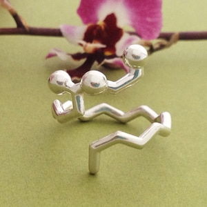 May include: A silver ring shaped like a chemical molecule. The ring is made of a series of connected spheres and lines.