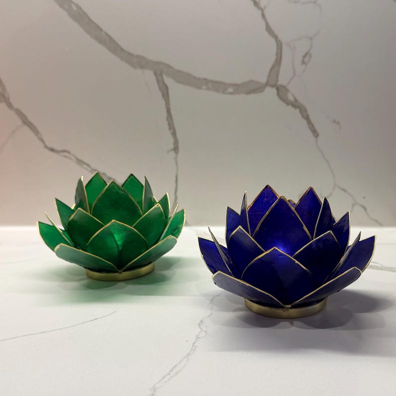 May include: Two lotus flower-shaped candle holders. One is a deep green with gold trim, and the other is a vibrant blue with gold trim. Both are on a gold base, creating a striking contrast. These decorative pieces add a touch of elegance.