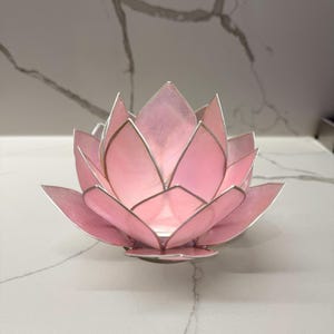 pink capiz shell tealight candle holder with silver trim on a marble countertop