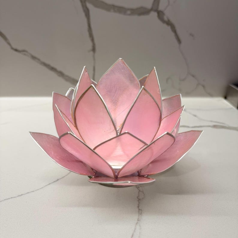 pink capiz shell tealight candle holder with silver trim on a marble countertop