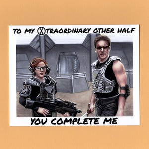 May include: A print featuring two figures in futuristic armor, with the text "TO MY EXTRAORDINARY OTHER HALF YOU COMPLETE ME." The artwork is a pencil sketch with a sci-fi theme, set against a gray background.