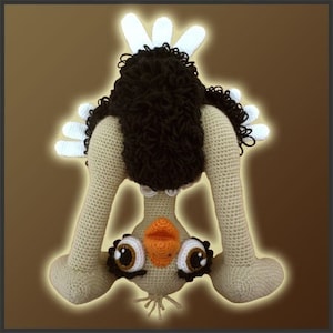 Puede incluir: Un juguete de peluche de avestruz de crochet de pie sobre su cabeza con las piernas en el aire. El avestruz es beige con plumas marrones y grandes ojos negros.