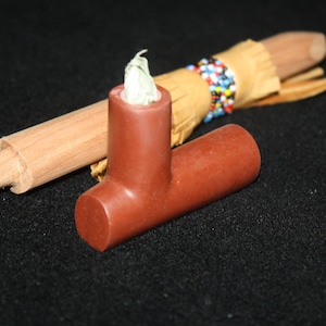 Könnte beinhalten: Eine traditionelle Pfeife im Stil der amerikanischen Ureinwohner mit einer braunen Tonschale und einem Holzstiel. Der Stiel ist mit Leder umwickelt und mit bunten Perlen verziert.