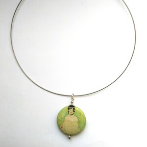 May include: A silver chain necklace with a round pendant featuring a painting of a woman in a green dress.