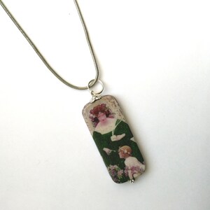 May include: A silver chain necklace with a rectangular pendant featuring a vintage image of a woman and a child in a garden setting.