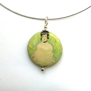 May include: A silver necklace with a round pendant featuring a painting of a woman in a green and yellow landscape. The pendant is attached to a silver chain.