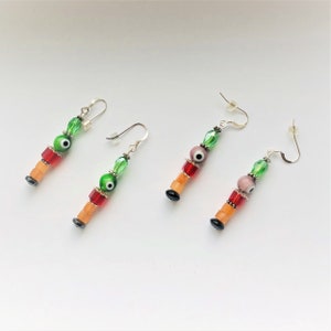 May include: A pair of dangle earrings with green, red, and orange beads. Each earring features a blue evil eye charm.