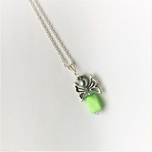 May include: A silver angel pendant necklace with a green bead and a pearl. The angel has wings and a pearl in the center of its chest.