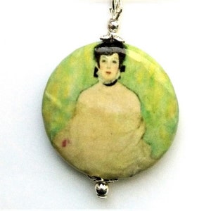 May include: A round pendant necklace featuring a painting of a woman in a white dress with a green background. The pendant is made of ceramic and has a silver chain.