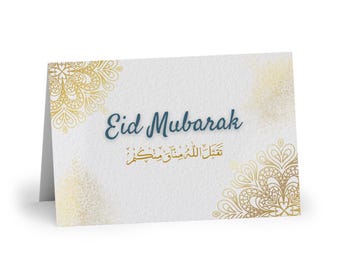 May include: A white card with a gold and white mandala design on the left and right sides. The card has the text "Eid Mubarak" in blue and Arabic text in gold.