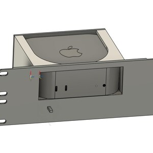 May include: A gray rack mount enclosure with a recessed area for a small computer. The computer has the Apple logo on top. The enclosure has several mounting holes and a rectangular opening for the computer's ports.