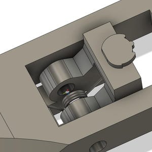 May include: A 3D-rendered mechanical component in shades of gray. The design features a central cylindrical element with a threaded screw, housed within a rectangular frame. A circular piece is visible on the right side, and the overall structure suggests a functional, possibly industrial, part.