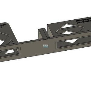 Puede incluir: Un soporte de rack de metal gris con formas geométricas recortadas y el texto "NetworkBook X2" y "NetworkBook REL-SHARED". El rack tiene aberturas rectangulares y orificios de montaje. El diseño es industrial y funcional.