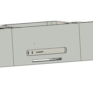 May include: A light grey computer component, rectangular in shape, featuring a central slot and several smaller openings. The component has a box-like structure with side panels and small holes along the edges.