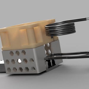 May include: A close-up of a mechanical component with a beige plastic housing, a silver metal frame with hexagonal cutouts, and a coiled wire element. A black plastic arm extends from the frame. The component is set against a gray background.