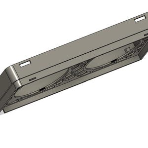 May include: A gray rectangular object with two circular indentations and a series of geometric patterns. The object has a rectangular shape with a slightly angled top and bottom. There are small rectangular cutouts on the top.