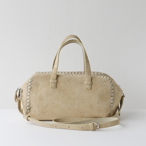 Puede incluir: Bolso de mano de ante beige con asa superior y bandolera extra&iacute;ble. El bolso presenta costuras decorativas en los bordes y herrajes plateados. El bolso mide aproximadamente 30 cm de ancho.