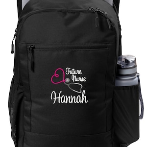 May include: Black backpack with a laptop inside and a water bottle in the side pocket. The front of the backpack features the text "Future Nurse" with a stethoscope and heart design, and the name "Hannah" in white.