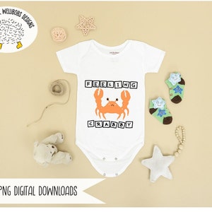 May include: White baby onesie with short sleeves and a graphic of a crab with the text "Feeling Crabby" in black block letters.