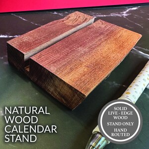 May include: A natural wood calendar stand with a solid live-edge design. The stand is hand-routed and features a warm, reddish-brown color. The text "NATURAL WOOD CALENDAR STAND" is visible on the left side of the image.