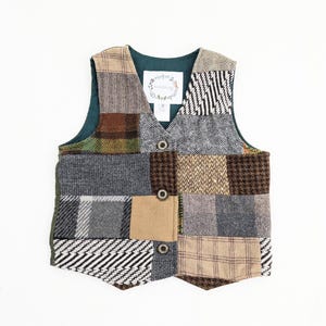 May include: A patchwork vest with a variety of textured fabrics in shades of brown, gray, and green. The vest has a dark green lining and three button closures. A small label is sewn on the inside.