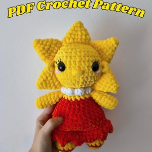 Pode incluir: Uma boneca de crochê feita à mão em forma de sol sorridente, com cabeça amarela e vestido vermelho. A boneca tem olhos pretos, bochechas rosadas e uma gola branca. O texto na parte superior diz "PDF Crochet Pattern".