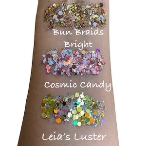 May include: Four different types of glitter, labeled "Bun Braids Bright", "Cosmic Candy", and "Leia's Luster".