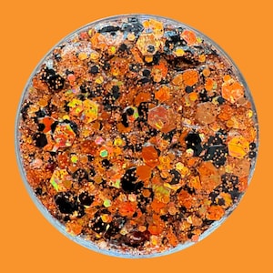 May include: A close-up of a jar filled with orange, black, and iridescent glitter. The glitter is a mix of different shapes and sizes.