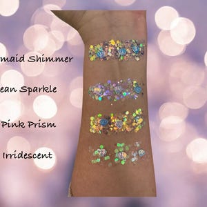 May include: Four swatches of glitter on a person's arm, labeled "Mermaid Shimmer", "Ocean Sparkle", "Pink Prism", and "Iridescent".