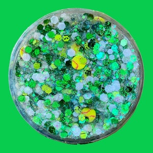 May include: A clear round container filled with green, white, and blue glitter and small yellow softball charms.
