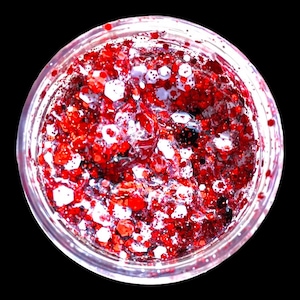 May include: A clear glass jar filled with red glitter and a clear gel. The glitter is densely packed and creates a shimmering effect.