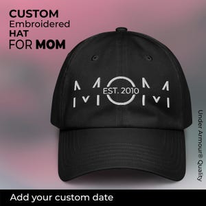 Puede incluir: Gorra de béisbol negra con texto bordado en blanco que dice "MOM EST. 2010".
