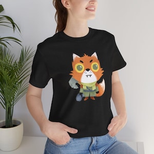 May include: Black t-shirt featuring a cartoon fox character with orange fur, green clothing, and a blue bag. The fox has large yellow eyes and a white muzzle. The shirt is made of a soft material.