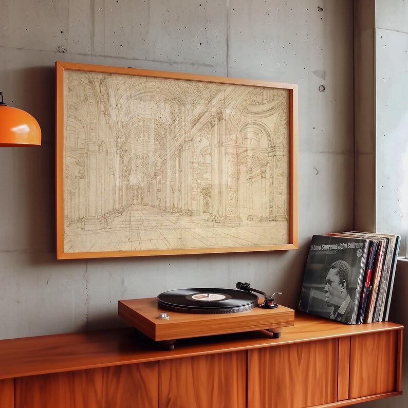 Op de afbeelding: Een ingelijste architectuurschets in een houten lijst hangt boven een houten platenspeler. Een stapel vinylplaten staat rechts. De platenspeler heeft een zwarte vinylplaat op de draaitafel.