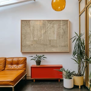 Op de afbeelding: Een ingelijste architectuurschets in neutrale tinten hangt boven een modern interieur uit het midden van de eeuw. De kamer heeft een bruinleren bank, een rode kast en potplanten. Een gele hanglamp en een grote spiegel dragen bij aan de inrichting.