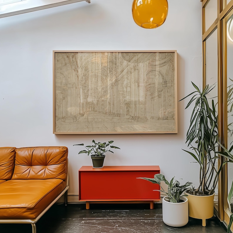 Op de afbeelding: Een ingelijste architectuurschets in neutrale tinten hangt boven een modern interieur uit het midden van de eeuw. De kamer heeft een bruinleren bank, een rode kast en potplanten. Een gele hanglamp en een grote spiegel dragen bij aan de inrichting.