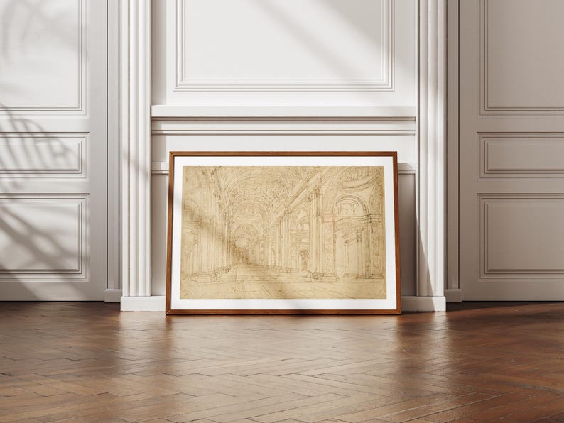 Op de afbeelding: Een ingelijste architectuurschets in een bruine houten lijst. De schets toont een gedetailleerd interieur met bogen, zuilen en een lange gang. Het kunstwerk staat tegen een witte muur met een schaduw en rust op een houten vloer.