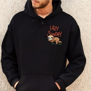 May include: Black hoodie with a pocket and a graphic of a sloth sleeping on a branch with the text "LAZY SUNDAY" in orange.
