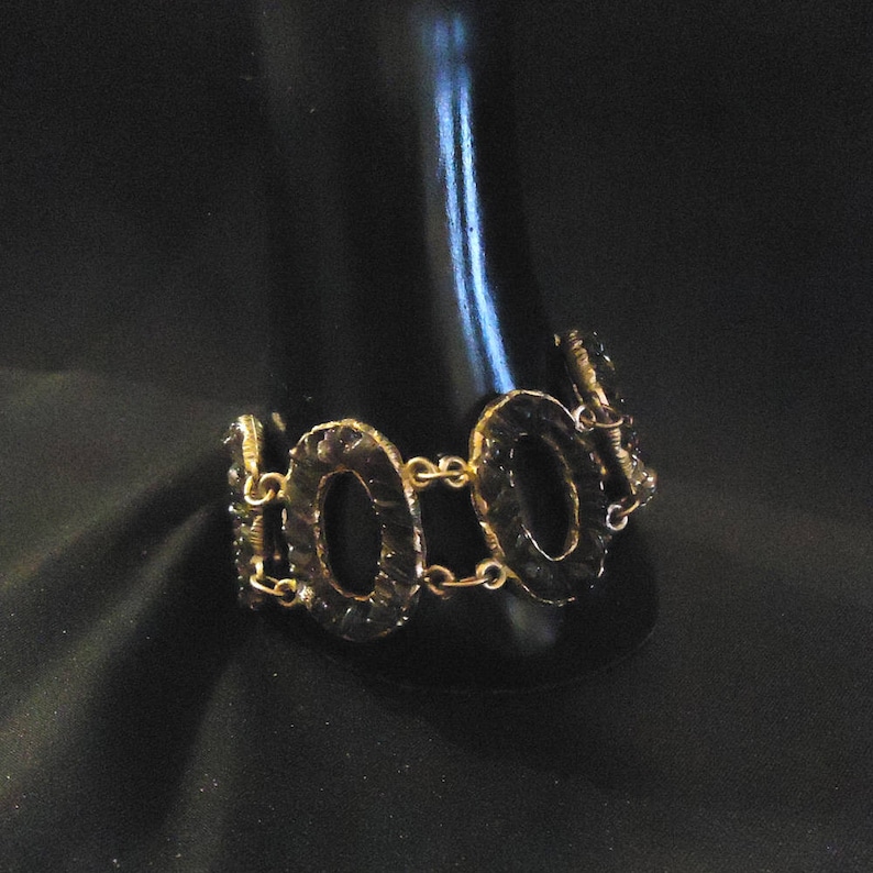 Peut inclure: Un bracelet dor&eacute; avec un design de cha&icirc;ne et des maillons ovales. Les maillons sont textur&eacute;s et ont une finition martel&eacute;e.