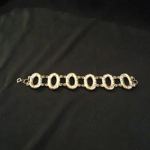 Peut inclure: Un bracelet en m&eacute;tal dor&eacute; avec un design de cha&icirc;ne et des maillons ovales. Le bracelet est en m&eacute;tal et a une finition polie.