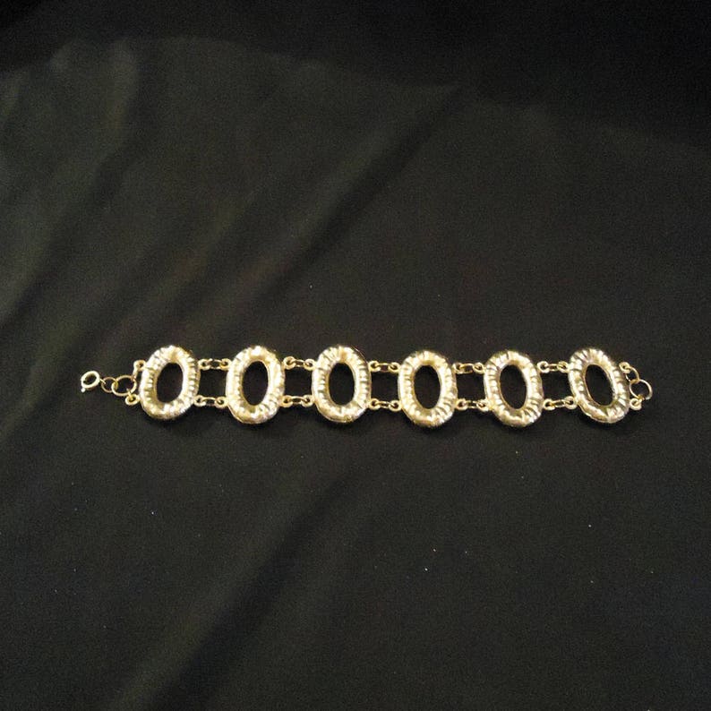 Peut inclure: Un bracelet en m&eacute;tal dor&eacute; avec un design de cha&icirc;ne et des maillons ovales. Le bracelet est en m&eacute;tal et a une finition polie.