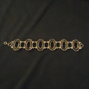 Peut inclure: Un bracelet en or avec des maillons ovales, chacun rempli de petites pierres brun fonc&eacute;.