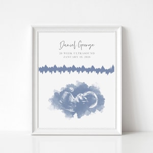 May include: A framed print featuring the name Daniel George, the text 20 WEEK ULTRASOUND JANUARY 19, 2026, a blue horizontal sound wave graphic, and a blue watercolor-style ultrasound image of a fetus centered on a white background.