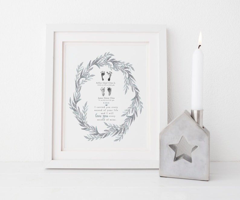 May include: A framed print with a watercolor wreath of leaves and two sets of baby footprints. The text reads "I carried you every second of your life and I will love you every second of mine."