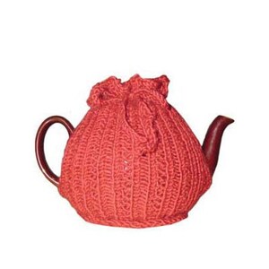May include: A red knitted tea cozy covers a brown teapot. The cozy has a ribbed texture and a drawstring closure at the top. The teapot has a curved handle and a spout.