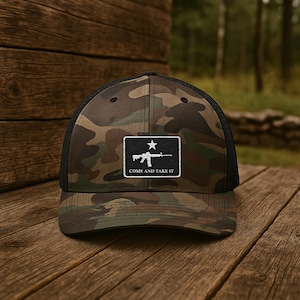 May include: A camouflage trucker hat with a black mesh back. The front of the hat features a white embroidered patch with a silhouette of a rifle and the text "Come and Take It".